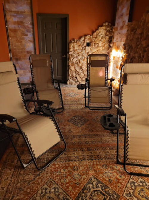 A cozy room with four reclining chairs arranged on a patterned rug, surrounded by stone walls.